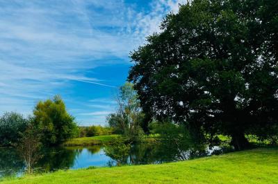 Salle de réception lumineuse avec tables en U décorées de nappes blanches, fleurs et bougies, murs en pierre apparente.