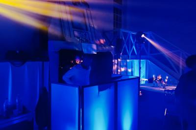 Des invités dansent joyeusement sous des lumières colorées dans une salle décorée pour une fête ou un mariage.