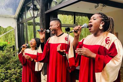 Des invités dansent joyeusement sous des lumières colorées dans une salle décorée pour une fête ou un mariage.
