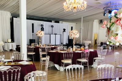 Des invités dansent joyeusement sous des lumières colorées dans une salle décorée pour une fête ou un mariage.