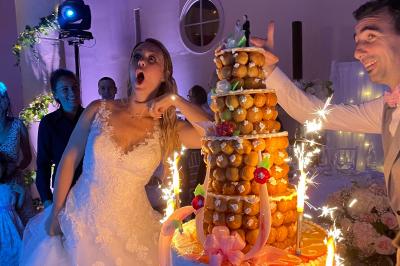 Des invités dansent joyeusement sous des lumières colorées dans une salle décorée pour une fête ou un mariage.