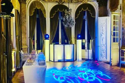 Des invités dansent joyeusement sous des lumières colorées dans une salle décorée pour une fête ou un mariage.