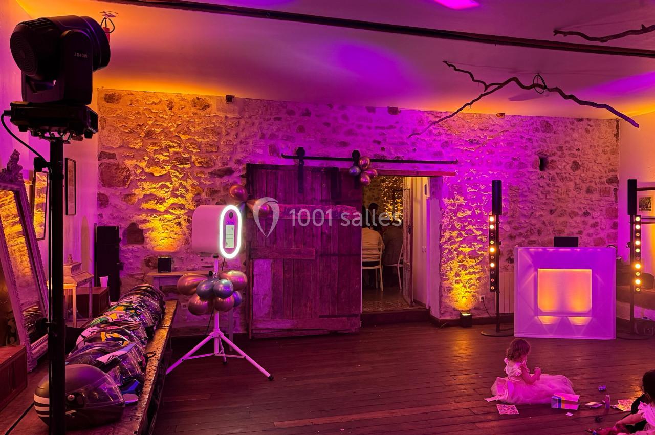 Salle décorée pour un événement avec éclairage coloré, ballons, et une enfant jouant au sol.