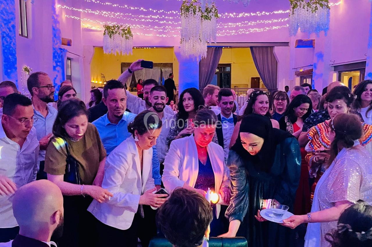 Groupe de personnes rassemblées dans une salle décorée, participant à une cérémonie avec des bougies.