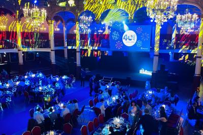 Des invités dansent joyeusement sous des lumières colorées dans une salle décorée pour une fête ou un mariage.