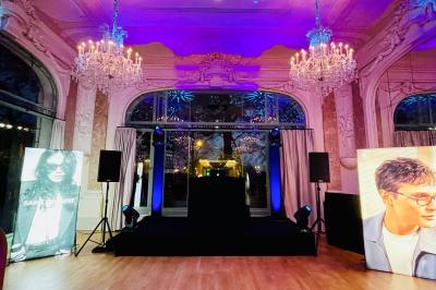 Des invités dansent joyeusement sous des lumières colorées dans une salle décorée pour une fête ou un mariage.