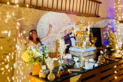 Un couple célèbre son mariage devant une pièce montée, entouré de décorations florales et d'étincelles festives.
