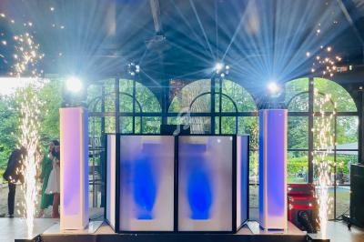 Installation lumineuse avec colonnes éclairées en bleu, jets d'étincelles et grandes baies vitrées en arrière-plan.