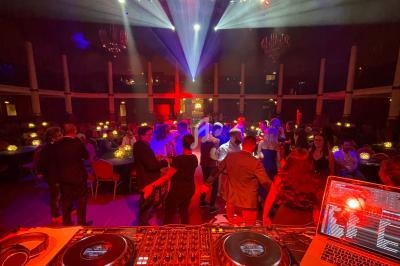 Vue depuis une table de mixage sur une piste de danse animée dans une salle éclairée par des jeux de lumière colorés.