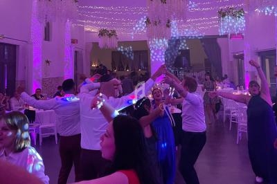 Des invités dansent sous des lumières colorées dans une salle décorée pour une réception festive.