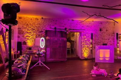 Des invités dansent joyeusement sous des lumières colorées dans une salle décorée pour une fête ou un mariage.