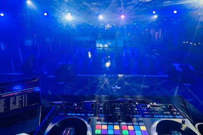 Des invités dansent joyeusement sous des lumières colorées dans une salle décorée pour une fête ou un mariage.