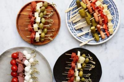 Buffet avec plusieurs plats chauds en marmites en inox, accompagné de sauces et d'assiettes en arrière-plan.