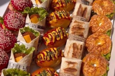 Buffet avec plusieurs plats chauds en marmites en inox, accompagné de sauces et d'assiettes en arrière-plan.