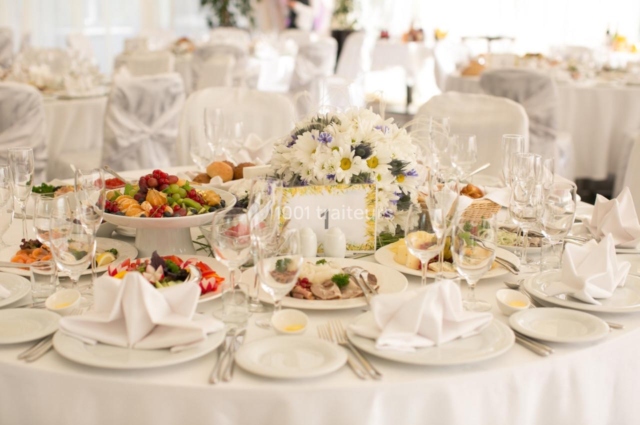Table élégamment dressée pour un événement, avec des fleurs, des plats variés et des couverts disposés soigneusement.