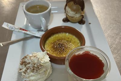 Buffet avec plusieurs plats chauds et froids présentés dans des récipients en inox sur une table noire.