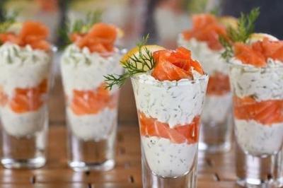 Buffet avec plusieurs plats chauds et froids présentés dans des récipients en inox sur une table noire.