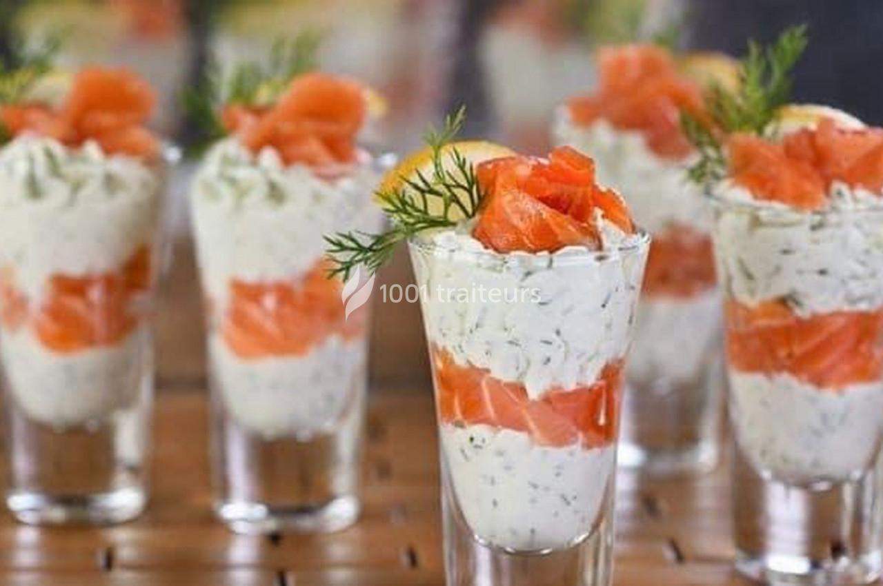 Verrines composées de crème aux herbes et de morceaux de saumon fumé, décorées d'aneth et de citron.
