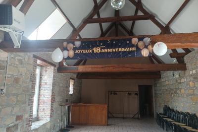 Salle de réception en pierre avec tables dressées, décorations florales et bougies, éclairée par la lumière naturelle.