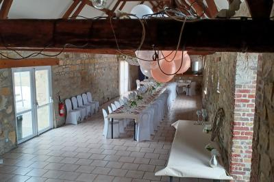 Salle de réception en pierre avec tables dressées, décorations florales et bougies, éclairée par la lumière naturelle.