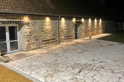 Salle de réception en pierre avec tables dressées, décorations florales et bougies, éclairée par la lumière naturelle.