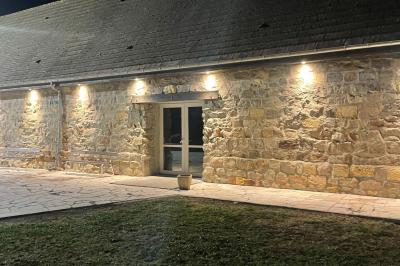 Salle de réception en pierre avec tables dressées, décorations florales et bougies, éclairée par la lumière naturelle.