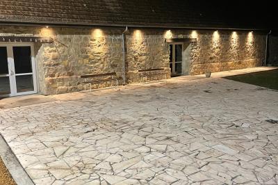 Salle de réception en pierre avec tables dressées, décorations florales et bougies, éclairée par la lumière naturelle.