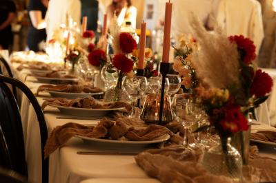 Salle de réception en pierre avec tables dressées, décorations florales et bougies, éclairée par la lumière naturelle.