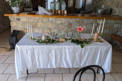 Arche décorée de feuillage et de tissu blanc avec deux chaises recouvertes, installées sur une pelouse devant un mur en…