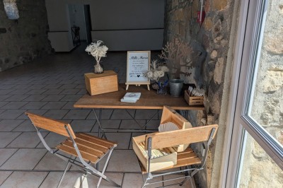 Arche décorée de feuillage et de tissu blanc avec deux chaises recouvertes, installées sur une pelouse devant un mur en…