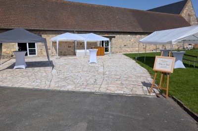 Arche décorée de feuillage et de tissu blanc avec deux chaises recouvertes, installées sur une pelouse devant un mur en…