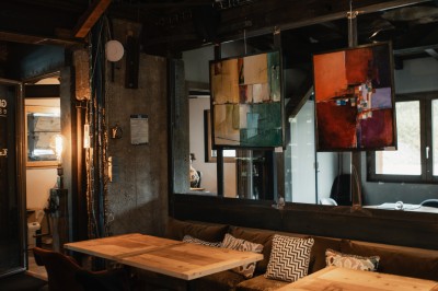 Table en bois avec verres à pied, carafe de boisson, herbes fraîches et décor intérieur lumineux et végétalisé.