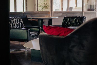 Table en bois avec verres à pied, carafe de boisson, herbes fraîches et décor intérieur lumineux et végétalisé.