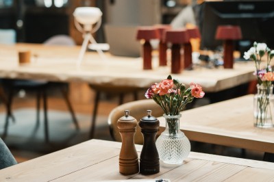 Table en bois avec verres à pied, carafe de boisson, herbes fraîches et décor intérieur lumineux et végétalisé.