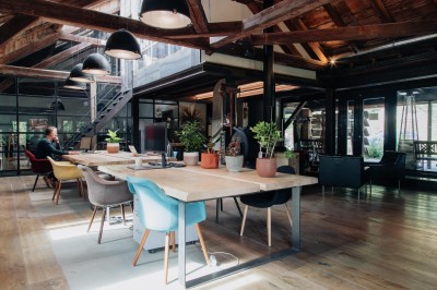 Table en bois avec verres à pied, carafe de boisson, herbes fraîches et décor intérieur lumineux et végétalisé.