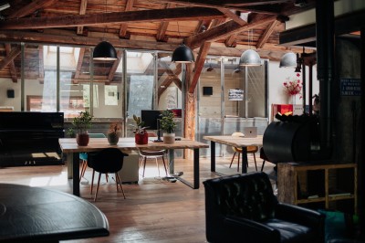 Table en bois avec verres à pied, carafe de boisson, herbes fraîches et décor intérieur lumineux et végétalisé.