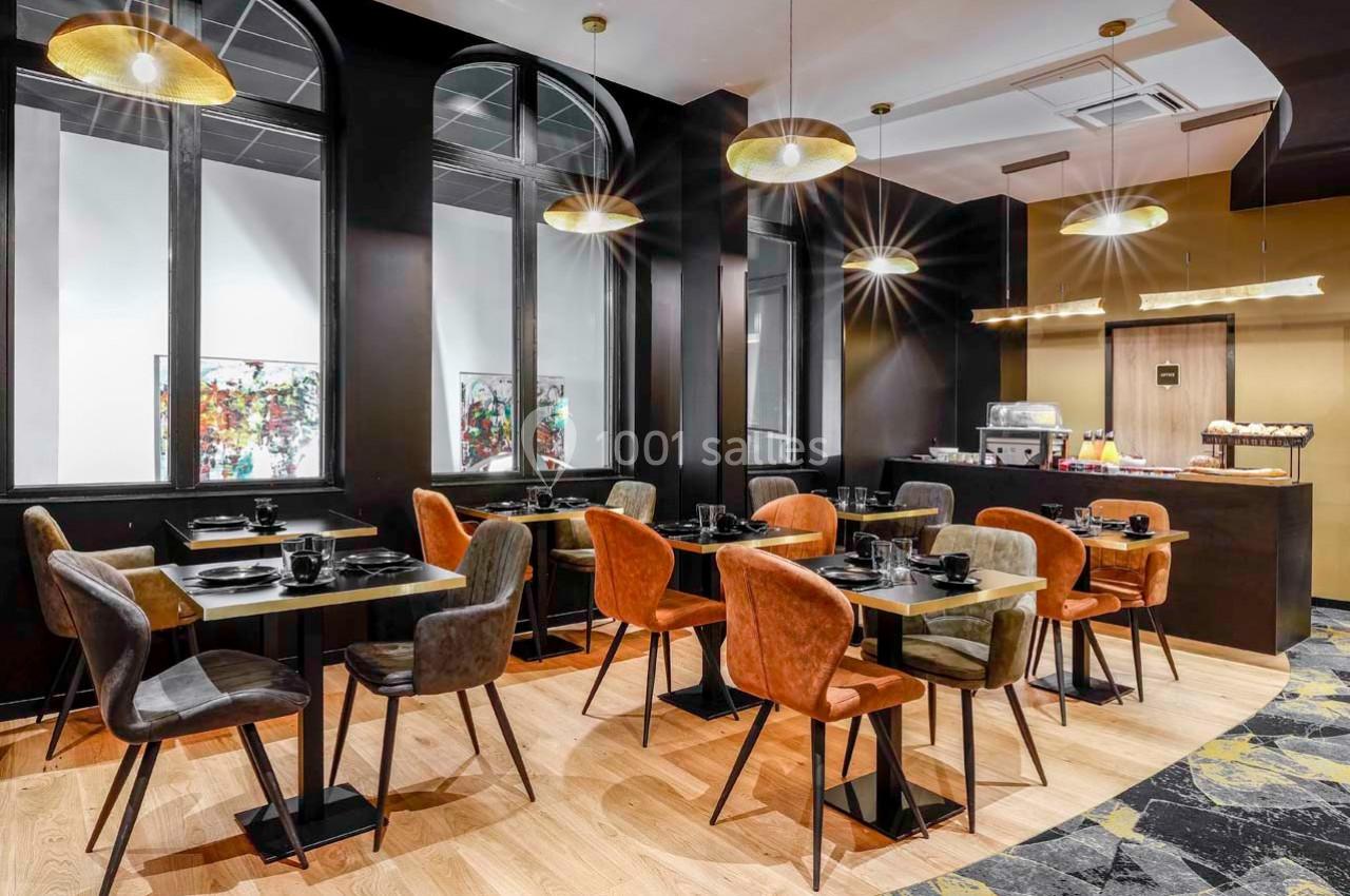 Salle de restaurant moderne avec tables dressées, chaises colorées et un coin buffet dans un décor chaleureux et lumineux.
