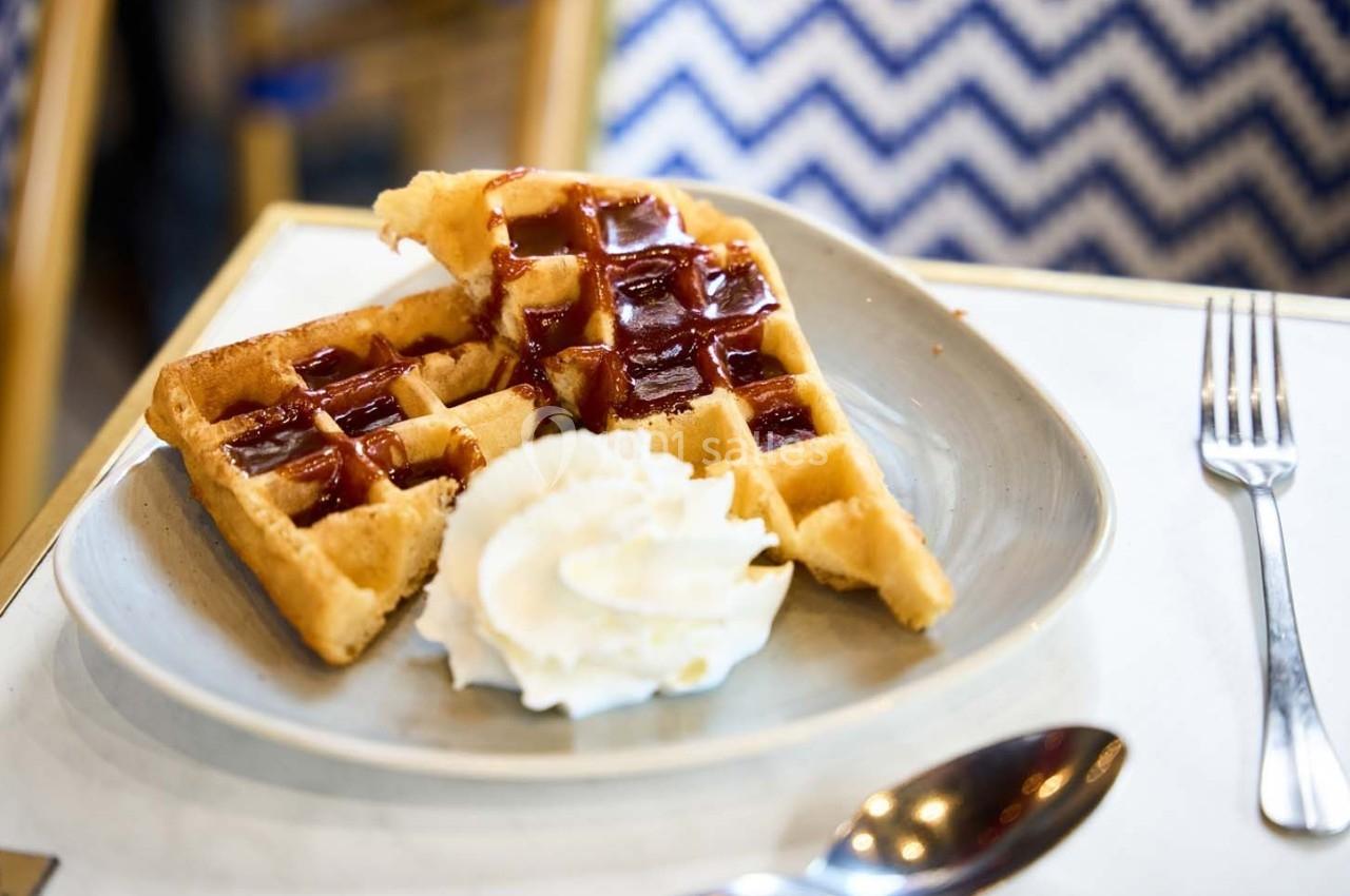 Gaufres dorées avec coulis de fruits rouges et crème chantilly, servies dans une assiette sur une table.