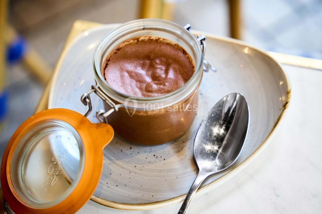 Pot de mousse au chocolat dans un bocal en verre ouvert, posé sur une assiette avec une cuillère en métal.