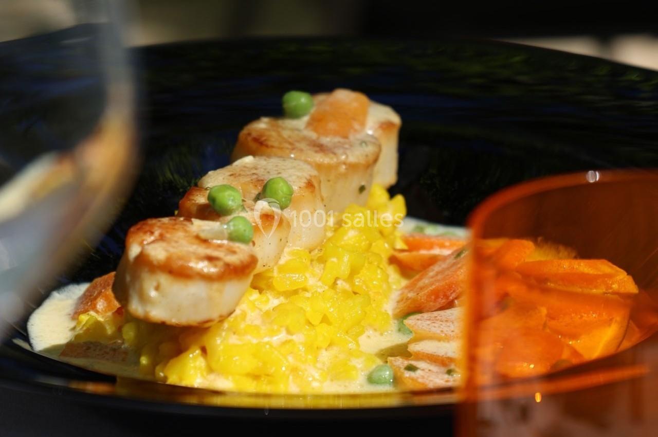 Noix de Saint-Jacques poêlées sur un risotto au safran, accompagnées de carottes et petits pois.