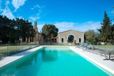 Vue aérienne d'un domaine avec piscine, jardins verdoyants, invités rassemblés et bâtiments en pierre.