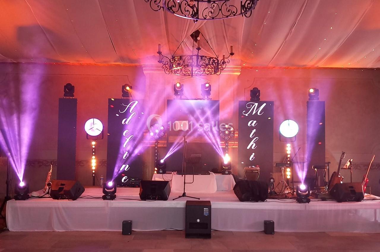 Scène décorée avec éclairages colorés, écrans lumineux et instruments de musique dans une salle de réception.