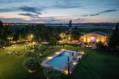 Vue aérienne d'un domaine avec piscine, jardins verdoyants, invités rassemblés et bâtiments en pierre.
