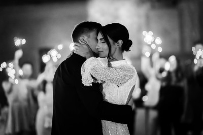 Un couple dansant tendrement lors d'une soirée, entouré de lumières scintillantes en arrière-plan.