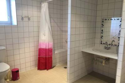 Dortoir avec plusieurs lits superposés en bois, matelas et oreillers, sur un sol carrelé clair.