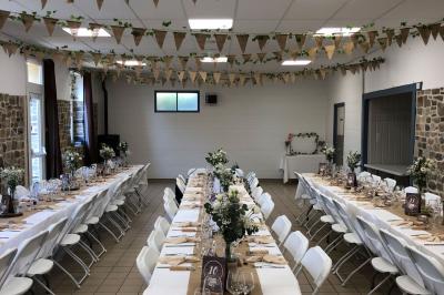 Dortoir avec plusieurs lits superposés en bois, matelas et oreillers, sur un sol carrelé clair.