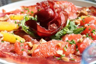 Assiette colorée composée de saumon fumé, courgettes en spirale, fraises et jeunes pousses sur un fond clair.