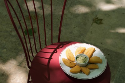 Table dressée avec assiettes, couverts, verres, serviettes et menu sur un set de table rond dans un restaurant.