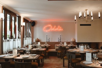 Table dressée avec assiettes, couverts, verres, serviettes et menu sur un set de table rond dans un restaurant.