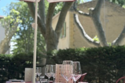 Table dressée avec assiettes, couverts, verres, serviettes et menu sur un set de table rond dans un restaurant.